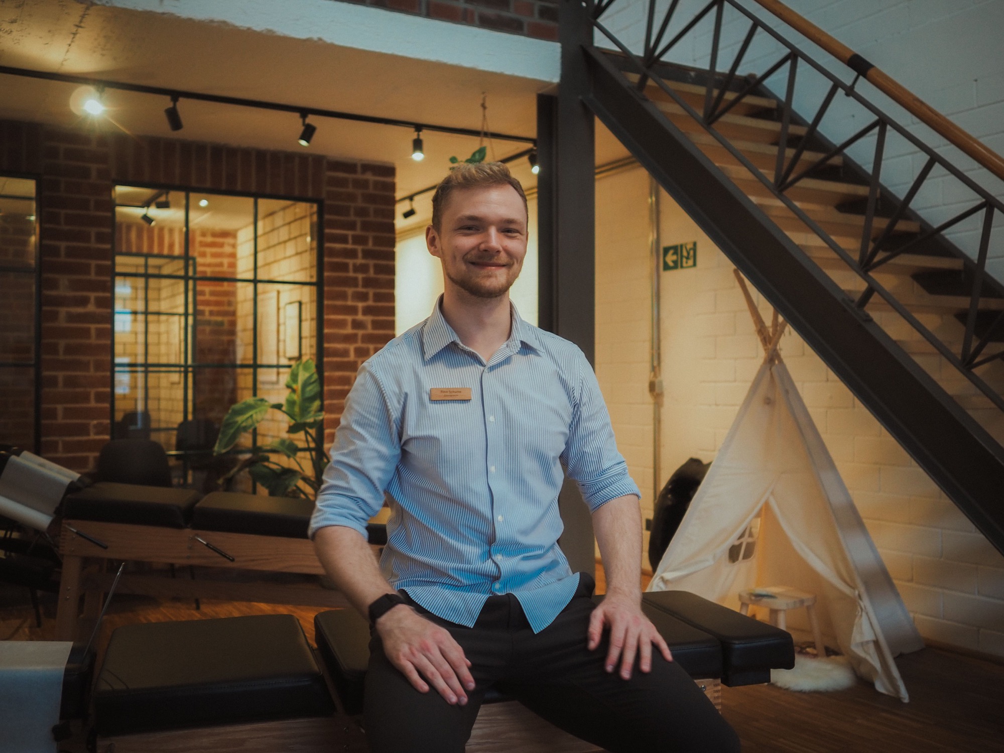 Finn Schütte, Chiropraktor, mit verschränkten Armen vor warmem, natürlichem Hintergrund